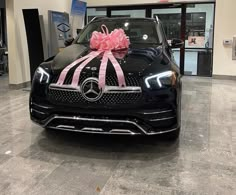 a black car with a pink bow on it's hood in a showroom