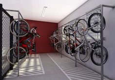 there are many bikes on the rack in this bike storage room with red walls and white flooring