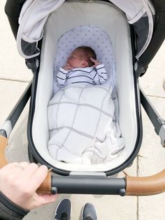 a baby in a stroller being held by someone