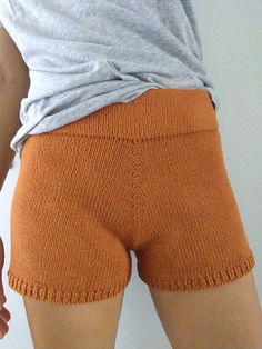 a woman wearing orange shorts with her hand on her hip and the back of her leg