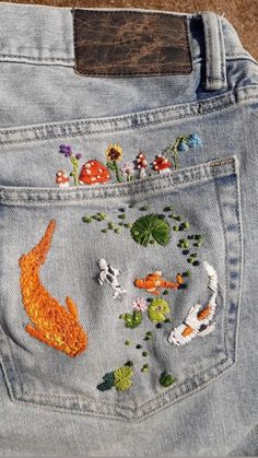 a pair of jeans with embroidered fish and flowers on them