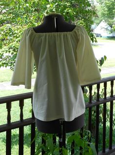 "Made to order This shirt is made from 100% cotton. It has elastic at the neckline and 3/4 length sleeves. Can be worn on or off the shoulder. The 3/4 length sleeve on this shirt makes it cooler for summer festival and faire wear! Available in Bleached White Muslin or Natural Muslin. (Also available different colors of 100% cotton and in a poly cotton blend - message me if you have a color request ). These are all good quality lightweight shirting fabrics. This is a loose fit shirt. Sized to fit Peasant Cotton Blouse For Gatherings, Peasant Style Cotton Blouse For Gatherings, Cotton Peasant Top For Gatherings, Fitted Cotton Peasant Top, Fitted Cotton Peasant Top Cottagecore Style, Fitted Cotton Peasant Top For Daywear, Fitted Cotton Peasant Top In Cottagecore Style, Fitted Cotton Tops For Gatherings, Wench Costume