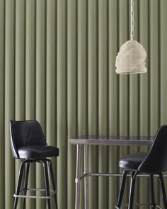 two stools and a table in front of a green wall with vertical slats