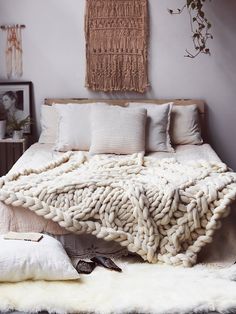 a bed with blankets and pillows on top of it in a bedroom next to a wall hanging