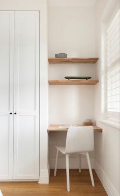 a white chair sitting in front of a desk and book shelf next to a window