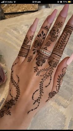 a woman's hand with henna tattoos on it and her hands in the background