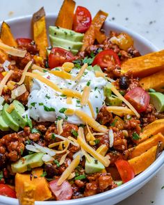 a white bowl filled with taco salad topped with sour cream