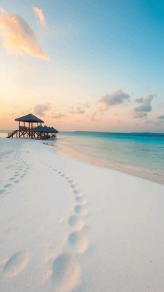 footprints in the sand leading to a hut on an ocean beach