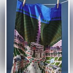 a towel hanging on a clothes line with buildings and trees in the city behind it