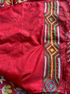 a red cloth with an intricate design on the front and back, laying on top of other fabric