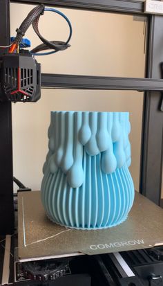 a large blue vase sitting on top of a metal table in front of a machine