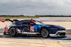 a car driving on a race track with an airplane in the background