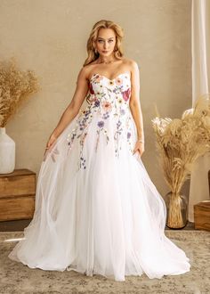 a woman in a white wedding dress standing next to a vase with flowers on it