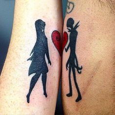 two people with tattoos on their arms holding a red heart and one has a black silhouette