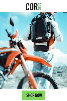 a man with a back pack on standing next to a dirt bike