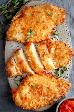 air fryer parmesan crusted chicken on a plate with sauce and herbs