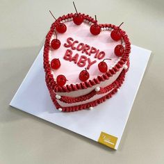 a heart shaped cake with the words scorppo baby written on it and cherries