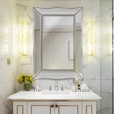 a bathroom with a sink, mirror and lights on the wall above it's counter