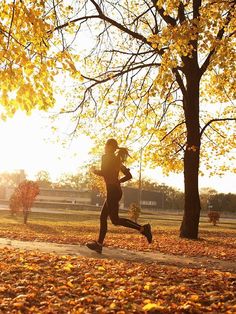 a person running in the park with leaves on the ground and trees all around them