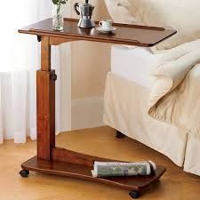 a wooden table with a laptop on it next to a bed