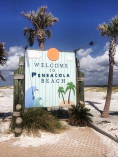 a welcome sign to the beach with palm trees