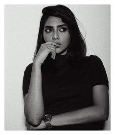 a black and white photo of a woman with her hand on her chin looking at the camera