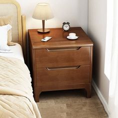 a nightstand with a lamp on top of it next to a bed and a night stand