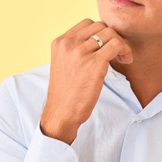 a man in a blue shirt is adjusting his ring on his left hand and looking off to the side