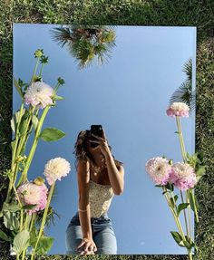 a woman taking a selfie in front of a mirror with flowers on the grass