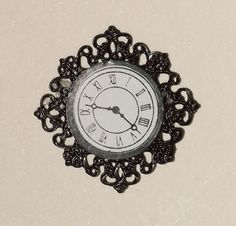 a black and white clock with roman numerals on it's face hanging from a wall