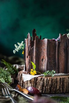 a piece of cake sitting on top of a wooden table next to forks and flowers