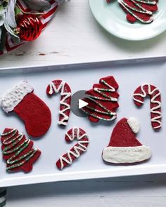 christmas cookies decorated with red and white icing are on a tray next to candy canes