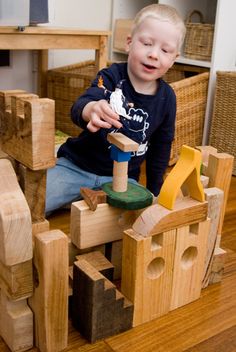 a young boy playing with wooden blocks on the floor