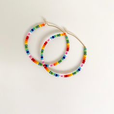 Colorful glass rainbow beads adorn a gold hoop earring. These lightweight earrings are so versatile. Gold Hoop Earring, Earrings Summer, Rainbow Glass, Rainbow Sprinkles, Rainbow Beads, Lightweight Earrings, Colorful Rainbow, Beaded Hoop Earrings, Beaded Hoops