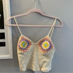 a crop top hanging on a hanger in front of a wall with a framed photograph