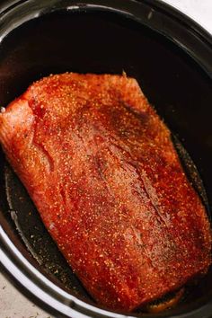 a piece of meat in a slow cooker with seasoning on it's side