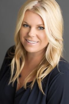 a woman with blonde hair and blue eyes smiling at the camera while wearing a black shirt