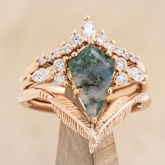 a fancy ring with a green stone surrounded by white diamonds on top of a wooden stand