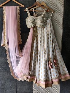 two dresses hanging up on a wall next to each other with laces and bows