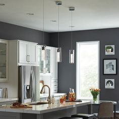 a kitchen with gray walls and white cabinets is pictured in this image, there are four chairs around the island