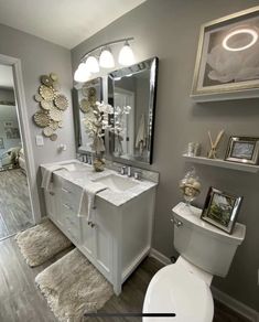 a white toilet sitting next to a sink in a bathroom under a mirror and lights