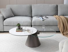 a living room with a couch, coffee table and books on the floor in front of it