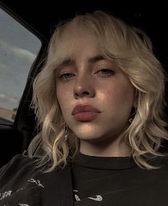 a woman with blonde hair sitting in the back seat of a car looking off into the distance