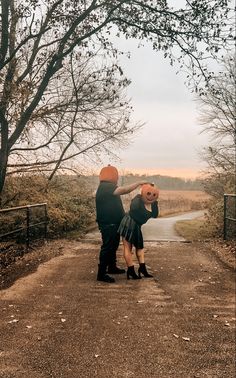 a man bending over on the side of a dirt road with trees in the background