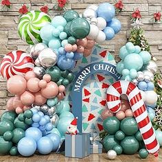 an arch decorated with balloons, candy canes and christmas decorations in front of a brick wall