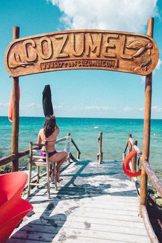 a woman sitting on top of a wooden pier next to the ocean