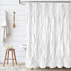 a white shower curtain in a bathroom next to a stool