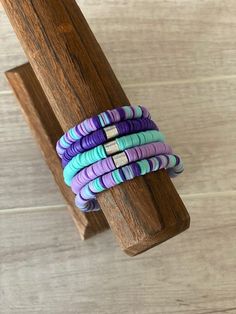 the bracelets are stacked on top of each other in purple, blue and green