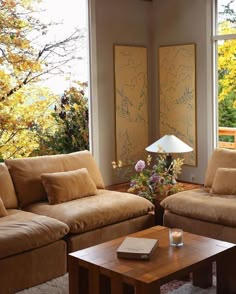 a living room with two couches and a coffee table in front of large windows