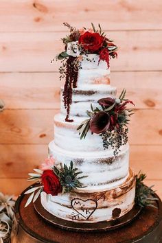 a three tiered wedding cake with red flowers and greenery on the top layer